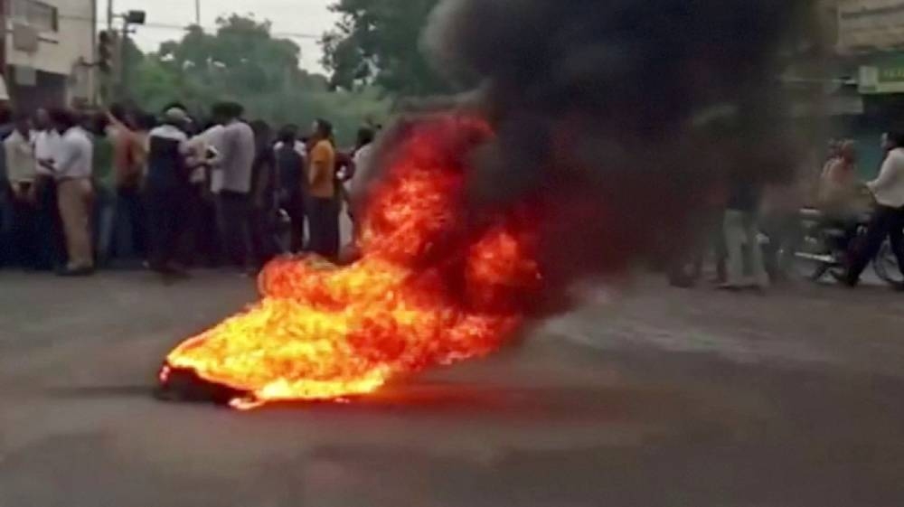 Smoke rises from a burning material while people gather on road as tensions rise after the killing of a Hindu man, in Udaipur, Rajasthan, India June 28, 2022 in this still image obtained from a handout video. — ANI handout via Reuters 
