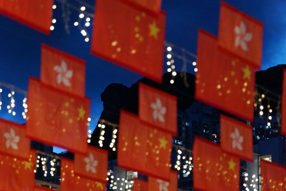 Hong Kong's Lion Rock is seen behind an installation of Chinese and Hong Kong flags in the city's Wong Tai Sin district on June 26, 2022 ahead the 25th anniversary of the Handover of Hong Kong from Britain to China which falls on July 1. ― AFP pic