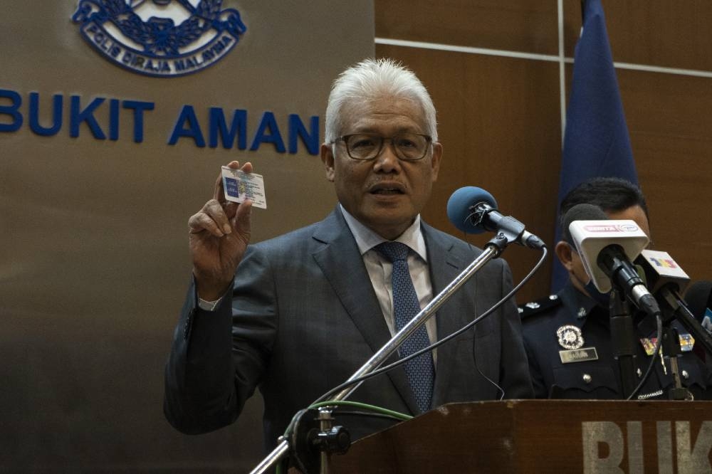 Datuk Seri Hamzah Zainudin holds up a fake identification card during a press conference at Bukit Aman in Kuala Lumpur on June 30, 2022. — Picture by Shafwan Zaidon