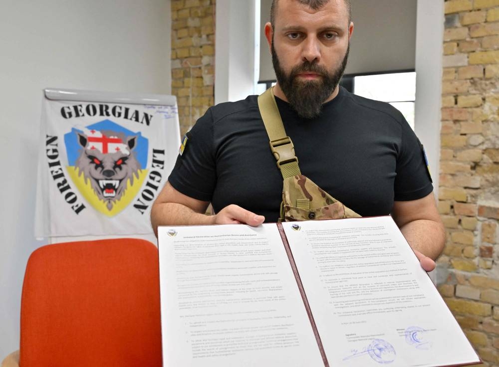 Head of the Georgian National Legion Mamuka Mamulashvili holds a folder with an agreement to observe international norms signed after a presentation organised by a Swiss NGO called Geneva Call in Kyiv on June 30, 2022 as a part of its efforts to meet and provide guidance to a wide range of Ukrainian combatants. ― AFP pic