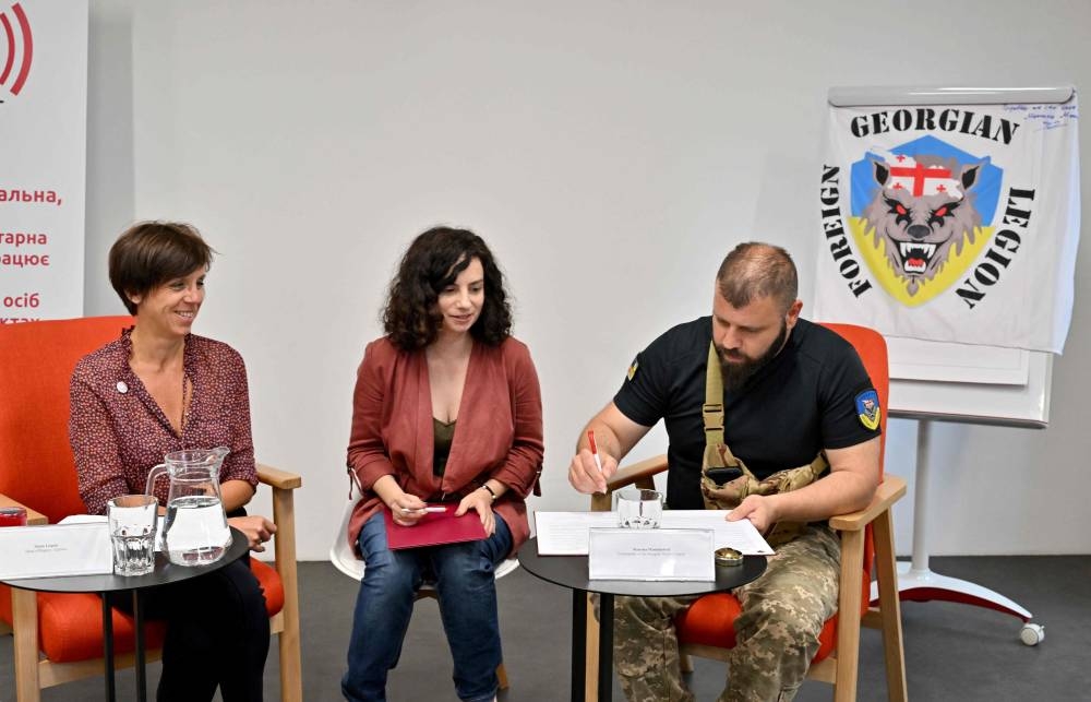 Marie Lequin (left), head of Geneva Call Eurasia region, watches as the head of the Georgian National Legion Mamuka Mamulashvili (right) sign an agreement to observe international norms after a presentation organised by a Swiss NGO called Geneva Call in Kyiv on June 30, 2022 as a part of its efforts to meet and provide guidance to a wide range of Ukrainian combatants. ― AFP pic
