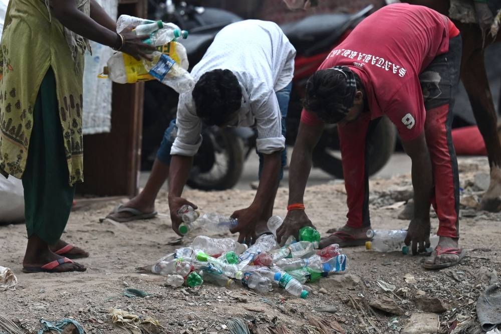 People collect plastic bottles for recycling in New Delhi on June 30, 2022. ― ETX Studio pic