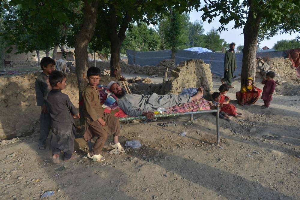 In this photograph taken on June 25, 2022, villagers sit outside their damaged house after a recent earthquake at Akhtar Jan village in Gayan district of Paktika province. ― AFP pic