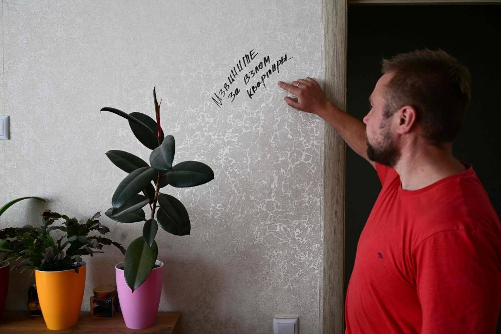 Biologist and gardener Yevgen Yelpitiforov, 37 years old, shows an inscription wrote in Russian on the wall of an apartment in Bucha, Kyiv region, that reads ‘Sorry for breaking down the door’, in one of houses and apartments entrusted to him by people who fled the war, on July 1, 2022. — AFP pic