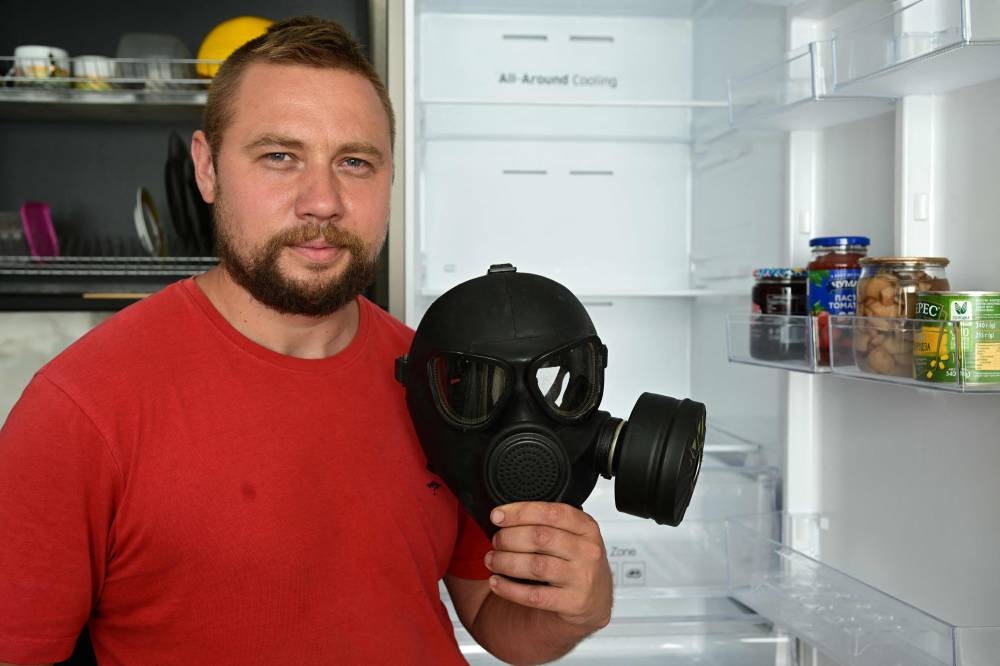 Biologist and gardener Yevgen Yelpitiforov, 37 years old, shows a gas mask left by the owners of one of houses and apartments entrusted to him by people who fled the war, in Bucha, Kyiv region, on July 1, 2022. — AFP pic