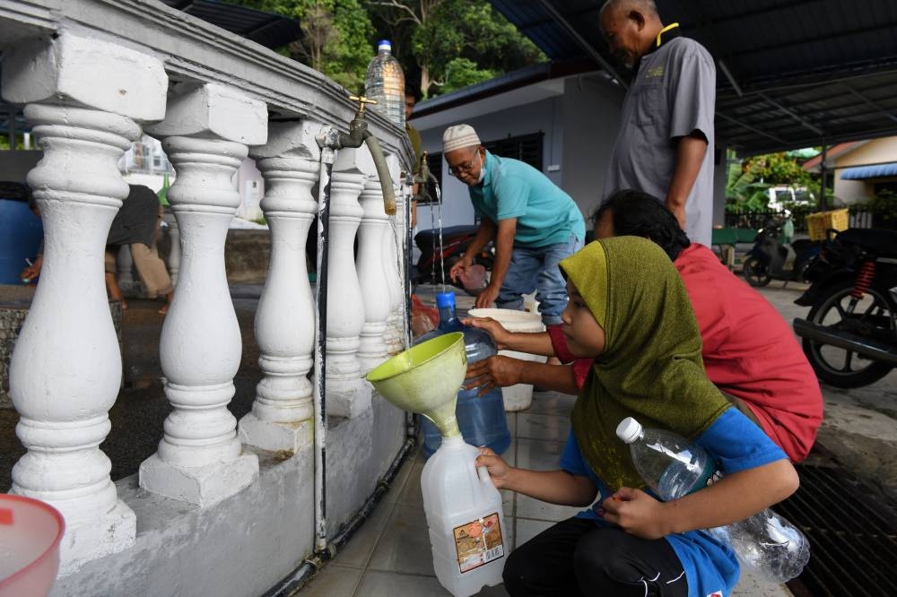 Members of the public collect water from Masjid Jamek Kampung Binjai in Batu Maung July 7, 2022. — Bernama pic