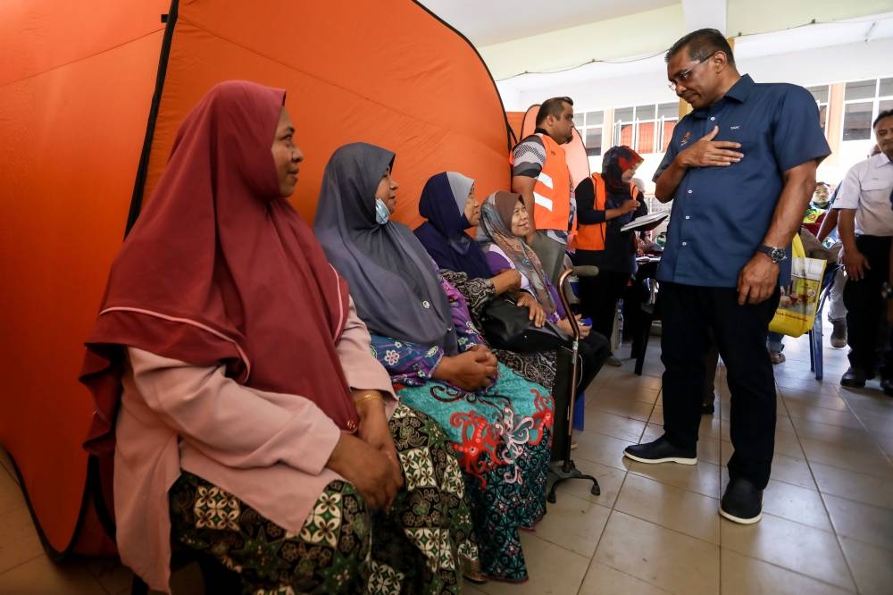 Datuk Seri Takiyuddin Hassan (right) speaks to flood evacuees at a temporary relief centre in Sekolah Menengah Kebangsaan Jerai, Kupang July 7, 2022. — Bernama pic