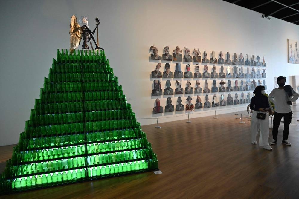 This picture taken on June 30, 2022 shows the artwork entitled ‘Monument That Guards Hankamnas’ (left-in green) at an exhibition by Indonesian artist Agus Suwage called 'The Theatre of Me' at the Macan Museum of Modern and Contemporary Art in Jakarta. — AFP pic