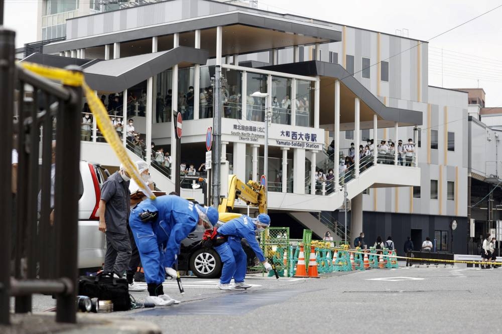 Investigators work around the scene where former Japanese Prime Minister Shinzo Abe was shot from behind by a man during an election campaign  in Nara, western Japan July 8, 2022. — Reuters pic