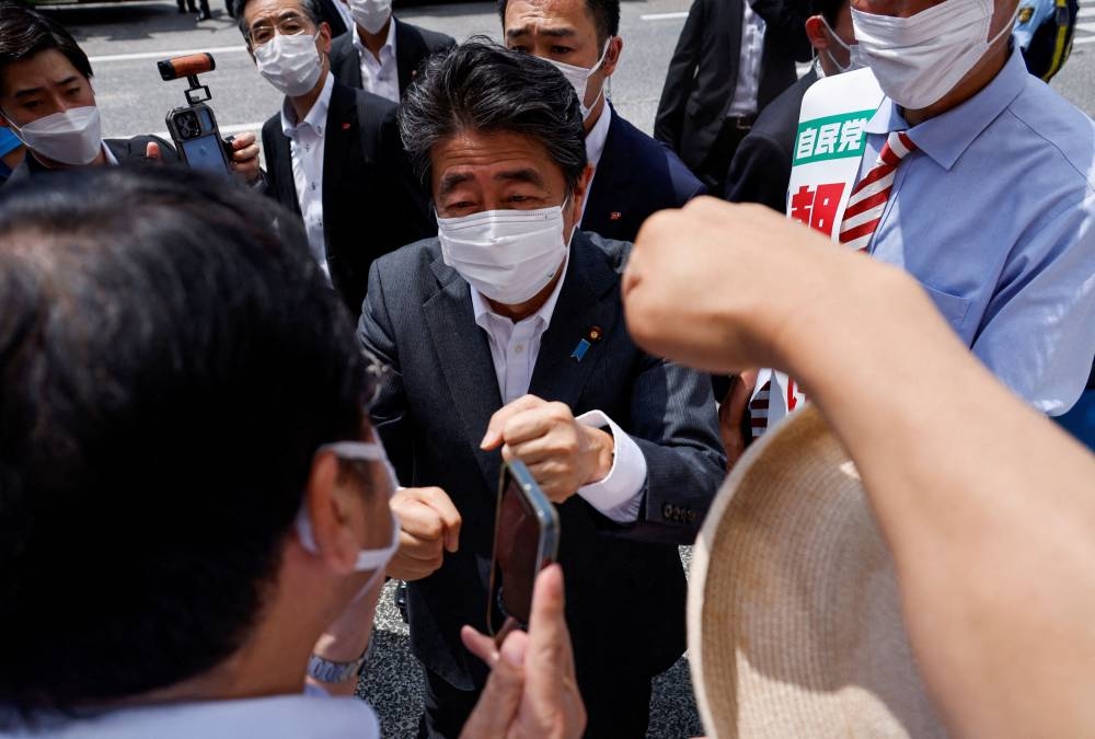 Former Japanese prime minister and ruling Liberal Democratic Party lawmaker Shinzo Abe bumps fists with voters after delivering a campaign speech as election campaign officially kicks off for the July 10, 2022 Upper House election. — Reuters pic
