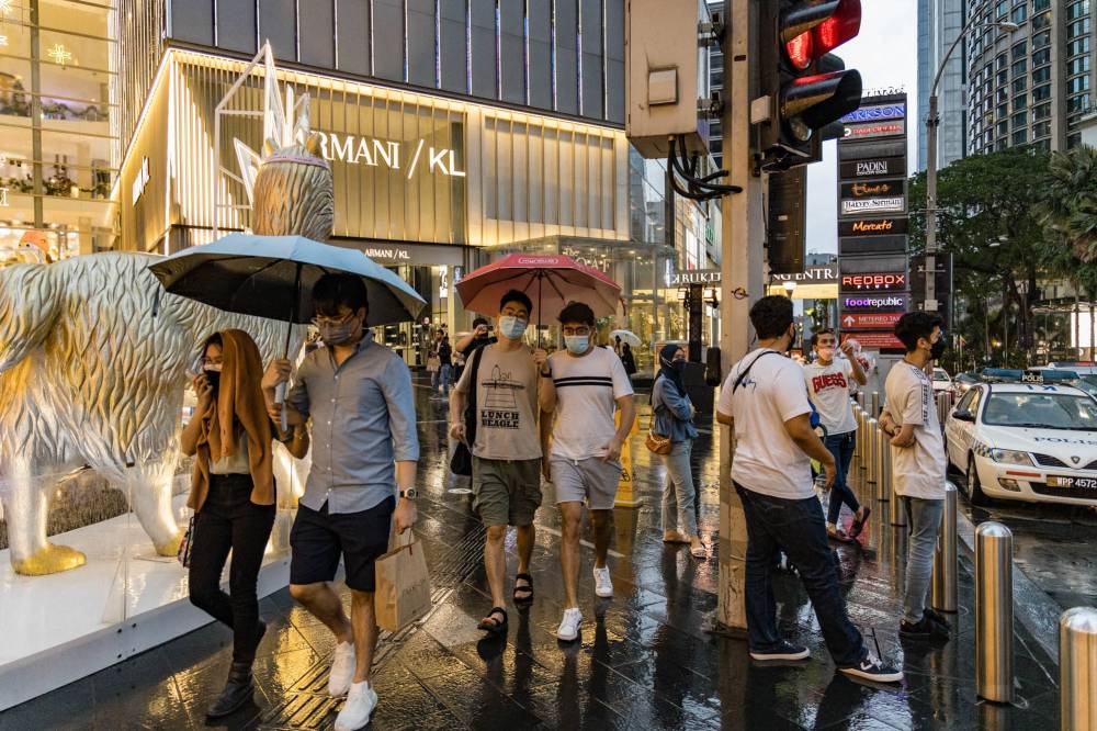People hold umbrellas cross a street during a rainy day in Kuala Lumpur on January 2, 2022. Picture by Firdaus Latif    