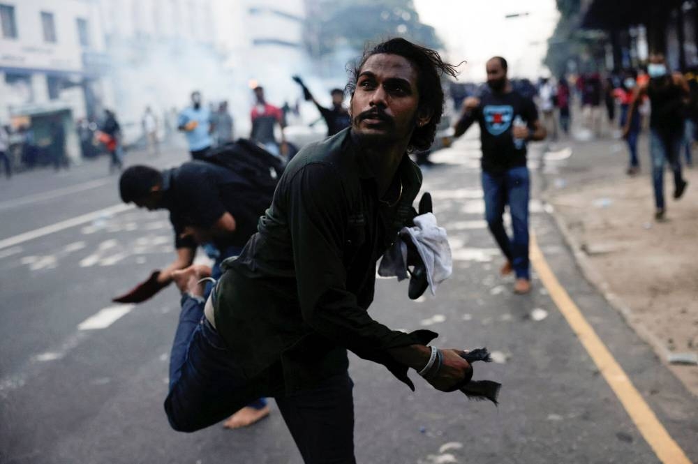 A demonstrator throws back a tear gas towards police members as police use tear gas and water cannons to disperse demonstrators near President’s residence during a protest demanding the resignation of President Gotabaya Rajapaksa, amid the country’s economic crisis, in Colombo, Sri Lanka, July 9, 2022. ― Reuters pic pic