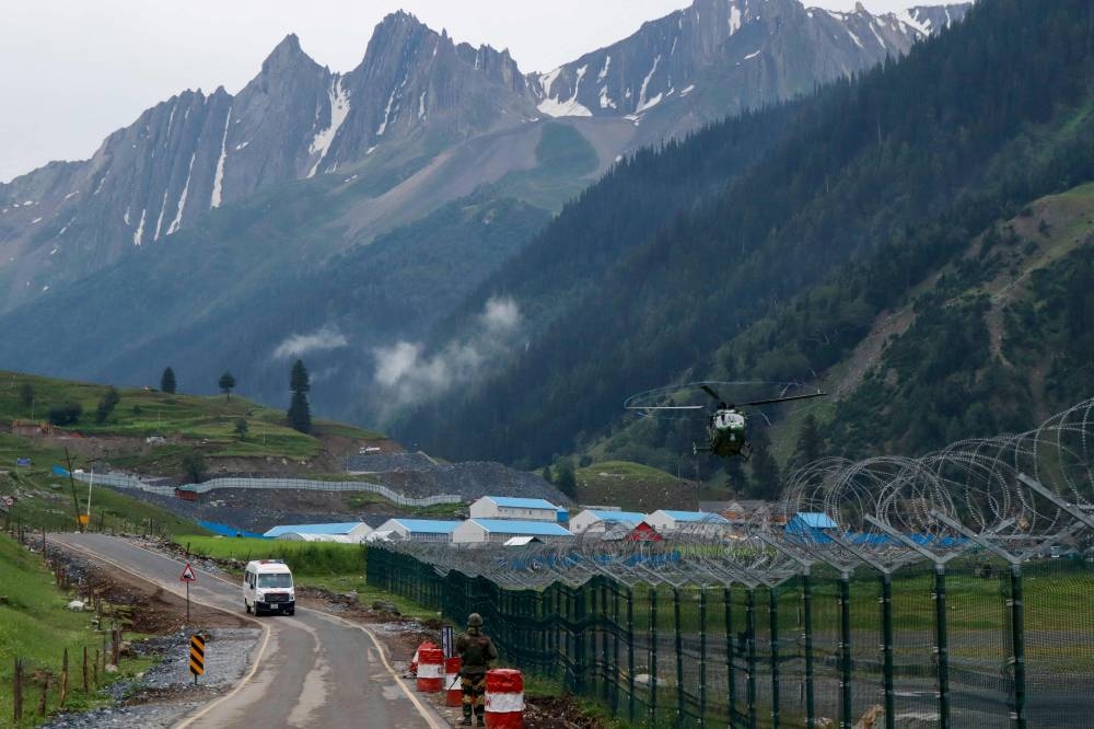 A helicopter carries flash flood affected victims of the Amarnath pilgrimage as an ambulance drives past near Baltal base camp in Kashmir on July 9, 2022. ― AFP pic