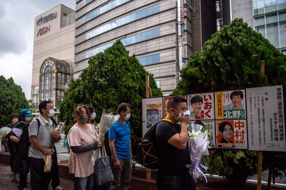 People line up to place flowers at a makeshift memorial outside Yamato-Saidaiji Station, where former Japanese prime minister Shinzo Abe was shot on July 8, in Nara on July 9, 2022. ― AFP pic