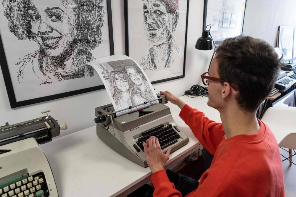 Artist James Cook poses for a photograph using a typewriter he uses to create pieces of art, in his studio in south-east London on July 1, 2022. — AFP pic