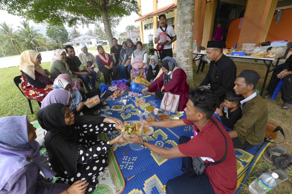 A family in Baling celebrates Hari Raya Aidiladha at the Sekolah Menengah Kebangsaan Jerai flood relief centre in Kupang July 10, 2022. — Bernama pic
