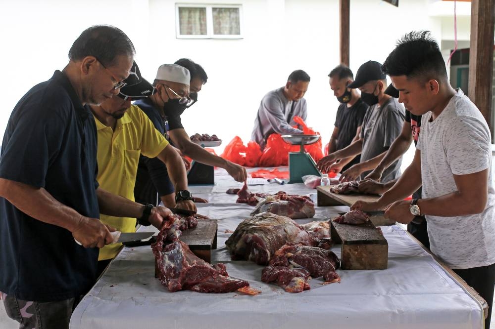 Kampung Dusun Nyior residents work together to cut up beef in conjunction with Hari Raya Aidiladha at Surau Ar Rajihah Al-Islamiah in Seremban July 10, 2022. — Bernama pic