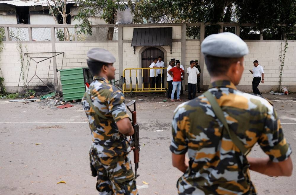 People stand next to the private residence of Prime Minister Ranil Wickremesinghe, after demonstrators burnt it during a protest against him, amid the country's economic crisis, in Colombo, Sri Lanka July 10, 2022. — Reuters pic