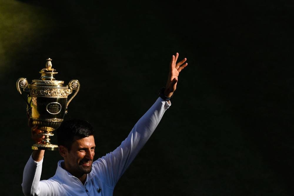 Serbia's Novak Djokovic poses with his trophy after defeating Australia's Nick Kyrgios during the men's singles final tennis match on the fourteenth day of the 2022 Wimbledon Championships at The All England Tennis Club in Wimbledon July 10, 2022. — AFP pic