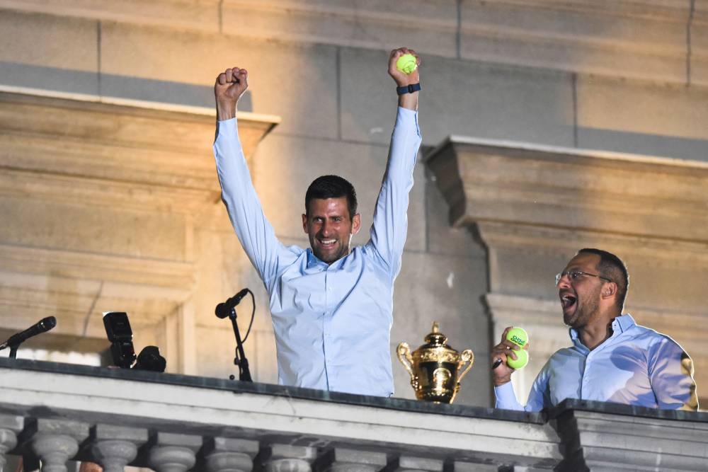 Serbian tennis player Novak Djokovic holds a tennis ball and waves to fans during a welcoming ceremony in front of the city hall, after he won his seventh Wimbledon title in Belgrade July 11, 2022. —  Reuters pic 