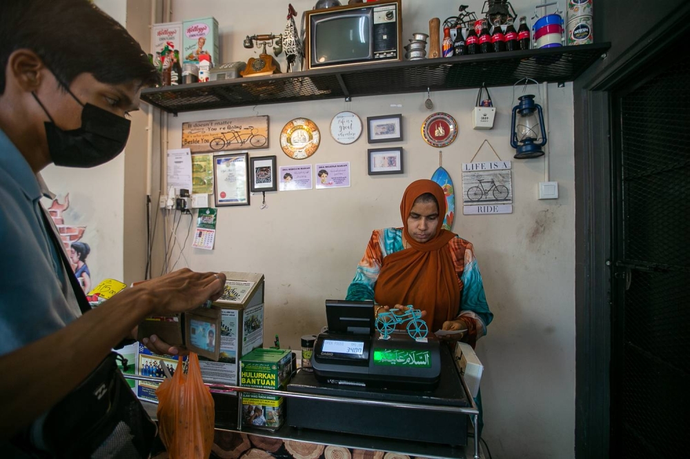 Katheesah Mohamed Gani handles the hordes of customers waiting to pay for their finished meals at the restaurant. Just a day prior, she was rushed to hospital owing to health issues caused by tiredness and stress. — Picture by Devan Manuel