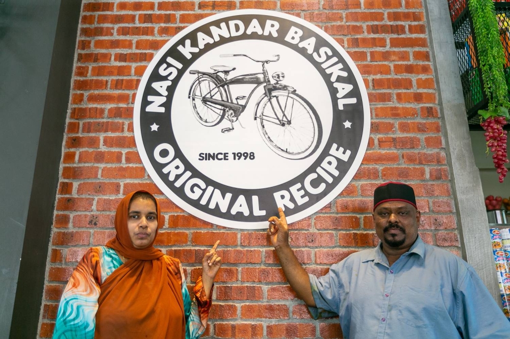 Katheesah Mohamed Gani and Mathana Shaib point at their signature logo at Nasi Kandar Basikal, June 23, 2022. — Picture by Devan Manuel
