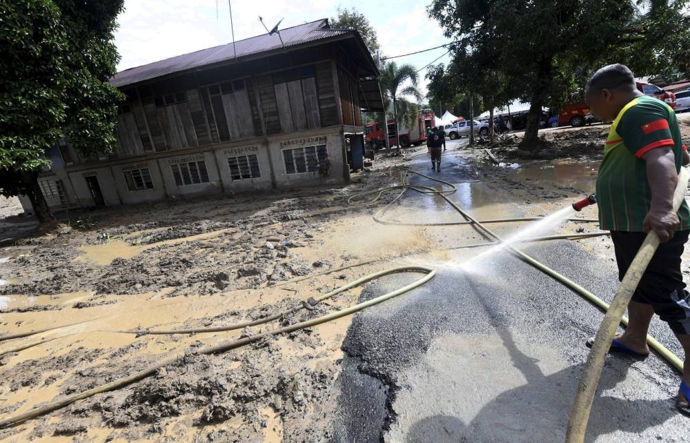 Fire and Rescue Dept personnel clean up homes badly affected by the floods in Baling, July 13, 2022. — Bernama pic 