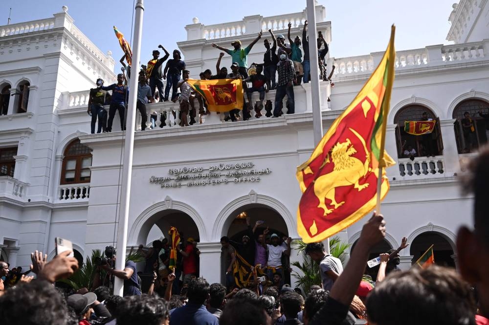 Demonstrators shout slogans and wave Sri Lankan flags during an anti-government protest inside the office building of Sri Lanka's prime minister in Colombo on July 13, 2022. — AFP pic