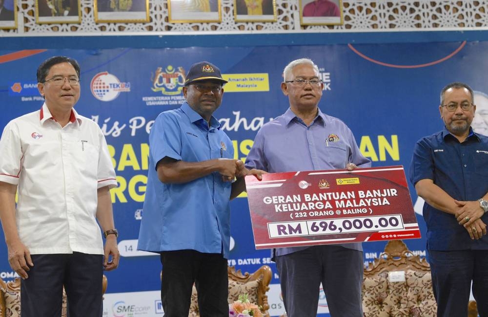 Entrepreneur Development and Cooperatives Minister Tan Sri Noh Omar (2nd right) hands over a mock cheque representing the Keluarga Malaysia Flood Aid (BBKM) grants totalling RM696,000 to Baling Member of Parliament Datuk Seri Abdul Azeez Abdul Rahim at Dewan Kenangan Tun Abdul Razak in Baling July 14, 2022. — Bernama pic