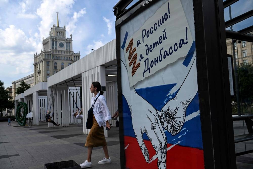 A woman walks past a poster reading ‘For Russia! For Donbass’ children!’ with the letter Z, which has become a symbol of support for Russian military action in Ukraine, in central Moscow on July 11, 2022. — AFP pic