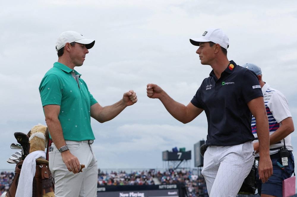 Northern Ireland's Rory McIlroy and Norway's Viktor Hovland celebrate on the 10th during the third round after scoring an eagle and a birdie respectively, July 16, 2022. — Reuters pic 