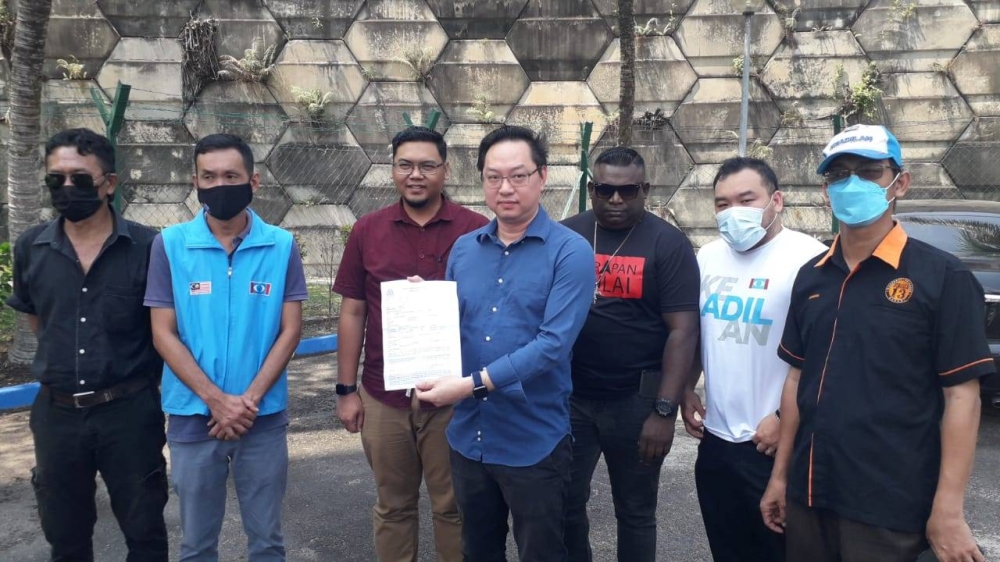 Johor PKR deputy chief Jimmy Puah Wee Tse (centre) holds up a copy of a police report outside the Tampoi police station in Johor Baru, July 19, 2022. — Picture by Ben Tan