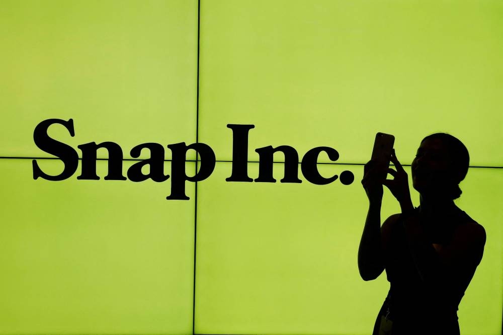 A woman stands in front of the logo of Snap Inc. on the floor of the New York Stock Exchange in New York City March 2, 2017. — Reuters pic
