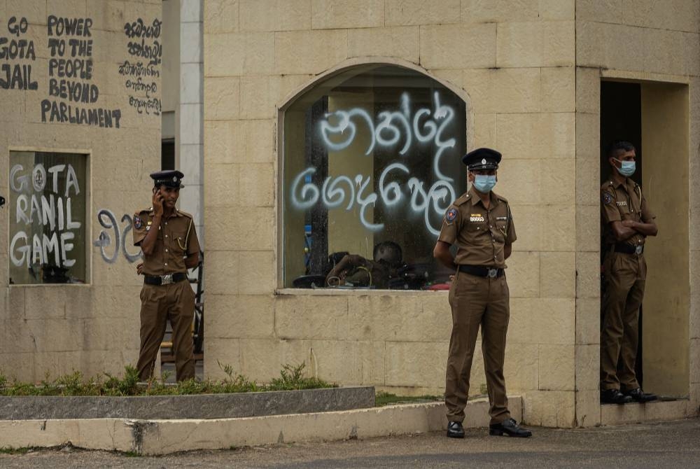 Policemen stand guard next to a graffitied wall following protests near the President's House, amid the country's economic crisis, in Colombo, Sri Lanka July 21, 2022. ― Reuters pic