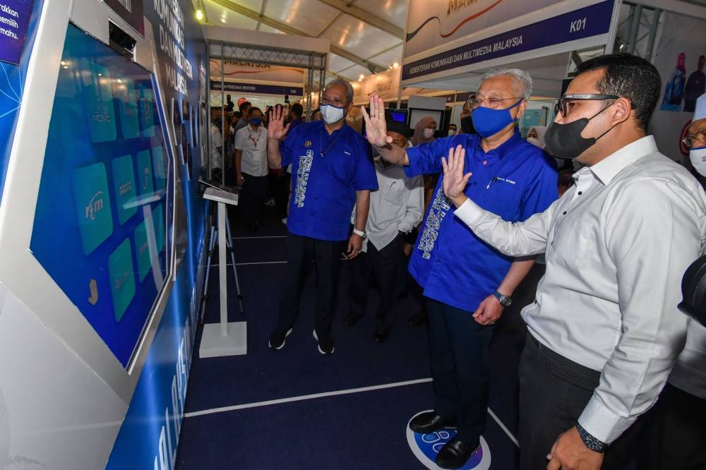 Prime Minister Datuk Seri Ismail Sabri Yaakob (second right) being briefed on using a chatbot while visiting the Ministry of Communications and Multimedia (K-KOMM) booth at the exhibition held in conjunction with the Kelantan Malaysian Family Aspirations (AKM) Tour Program at the Sultan Muhammad IV Stadium, Juky 23, 2022. — Bernama pic