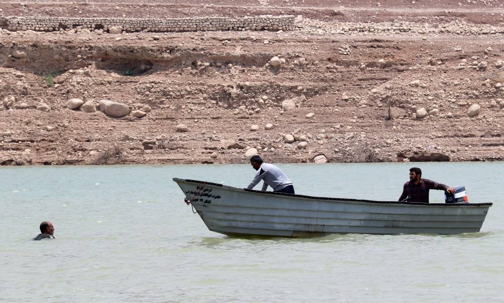 A picture obtained by AFP from the Iranian news agency Tasnim on July 23, 2022, shows people in a boat reaching a man in a river, after flooding caused by heavy rainfall in southern Iran's Estahban county, that reportedly killed at least 21 people. ― AFP pic