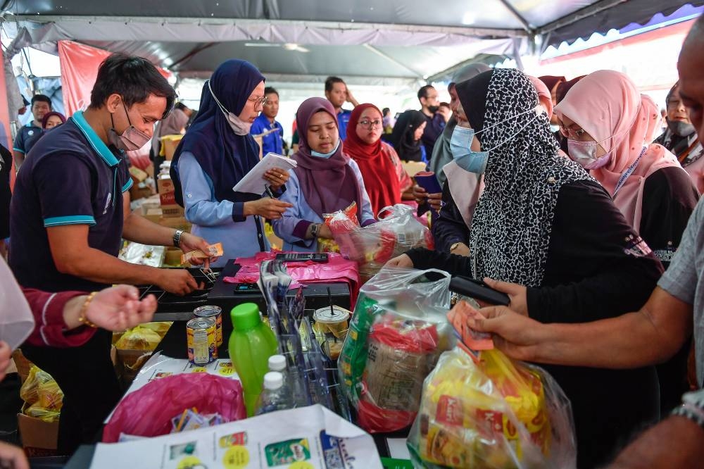 People queue to pay for basic necessities at the cashier on the last day of the Kelantan Malaysian Family Aspirations Tour (AKM) at the Sultan Muhammad IV Stadium in Kota Baru July 24, 2022. — Bernama pic