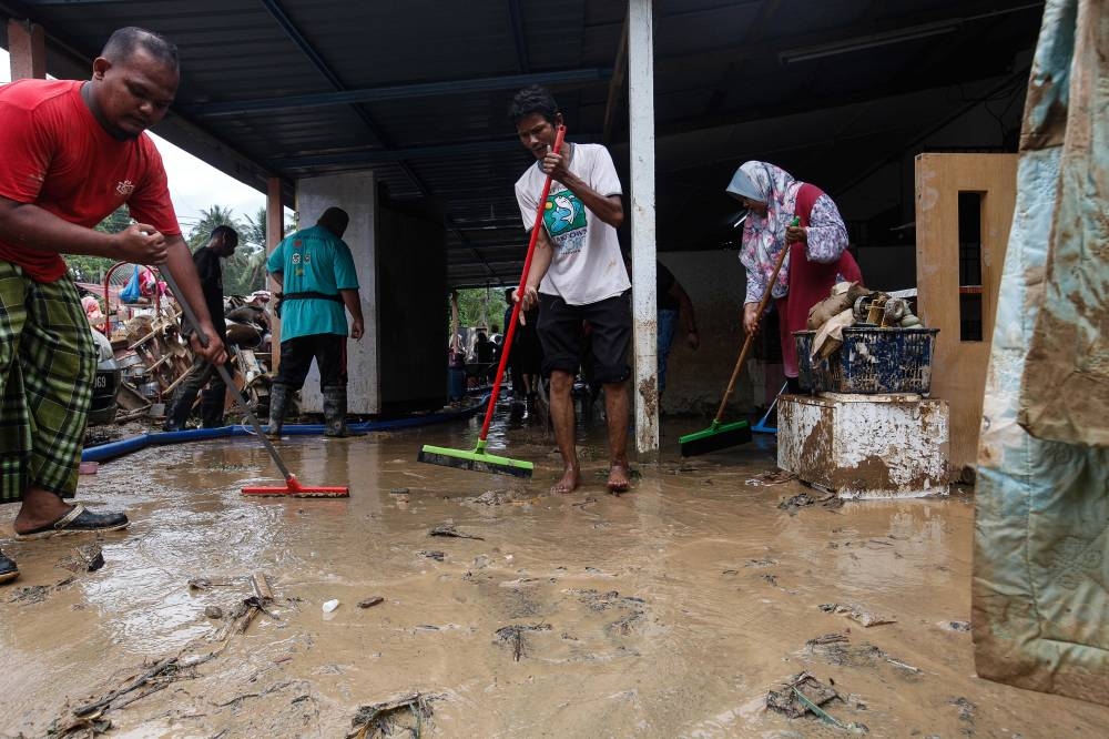 Residents are seen cleaning their house after flash floods hit their home at Kampung Iboi in Kedah July 5, 2022. ― Picture by Sayuti Zainudin