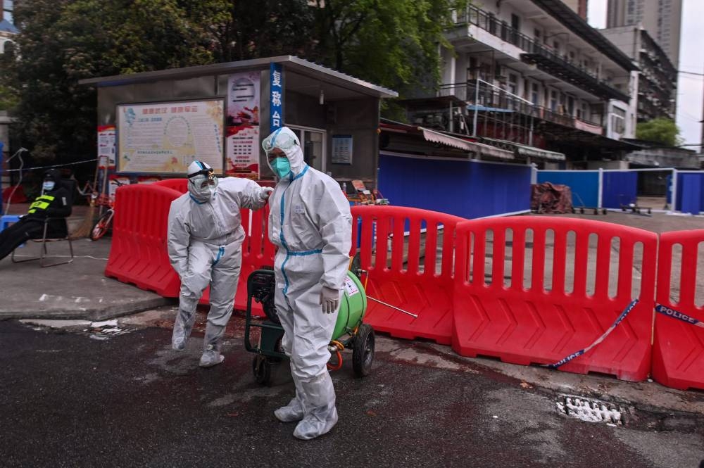 n this file photo taken on March 30, 2020, workers wearing protective suit walk next to Huanan Seafood Wholesale Market in Wuhan, in China's central Hubei province. — AFP pic