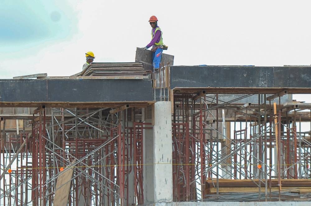 Construction workers walking across a platform at a building site in Kuala Lumpur on November 5, 2020. ― Picture by Shafwan Zaidon