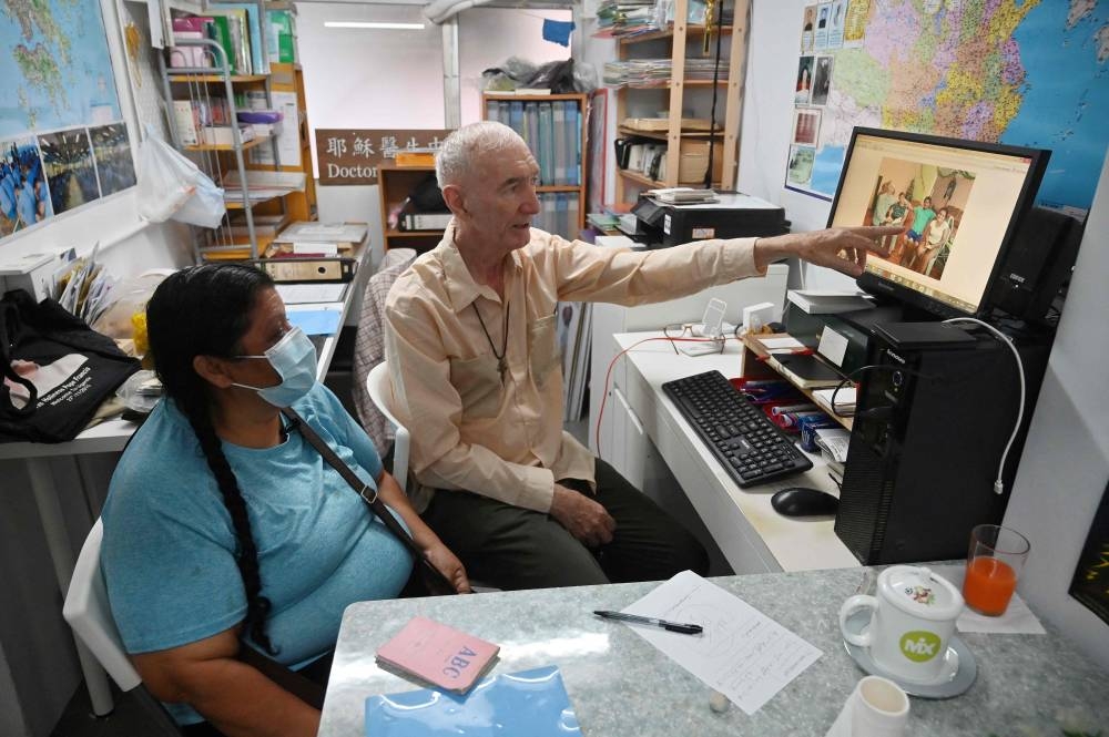 This photo taken on May 9, 2022 shows Zoila Lecarnaque Saavedra, recently released after serving time in prison for drug trafficking, talking to Father John Wotherspoon, a Catholic prison chaplain who has spent decades working with drug mules, in his office in the Jordan area of Hong Kong. — AFP pic