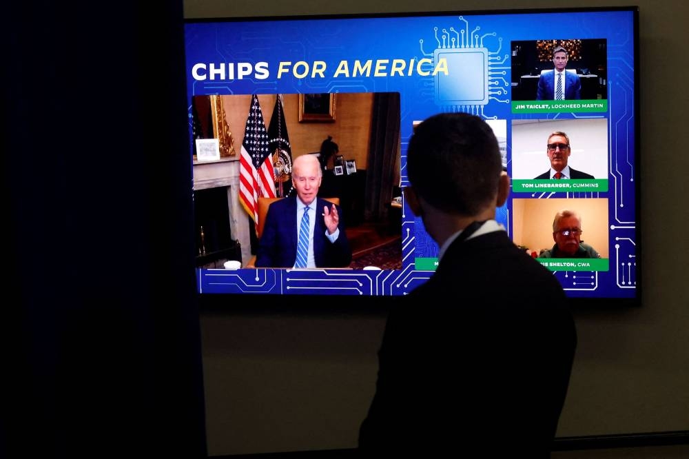 A White House press aide looks on as US President Joe Biden, isolating following his Covid-19 diagnosis, appears virtually in a meeting with business and labour leaders about the Chips Act — relating to US domestic chip and semiconductor manufacturing — in an auditorium on the White House campus in Washington July 25, 2022. — Reuters pic