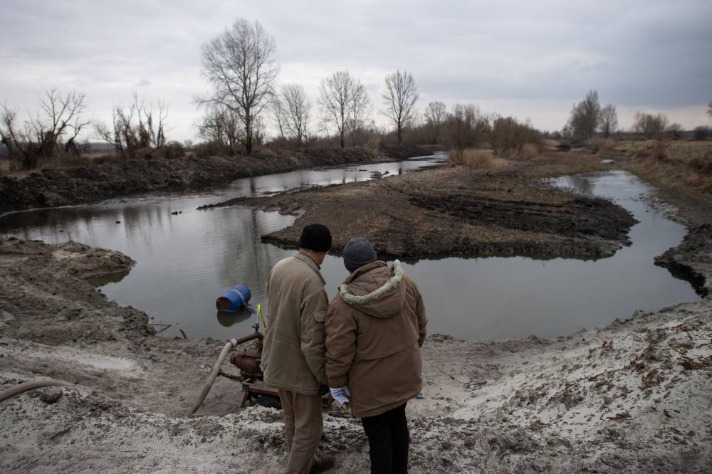 Ferenc Szepe, 68, a farmer, and his wife watch as remaining water is pumped in an attempt to refill a lake with groundwater, near Jaszszentlaszlo, Hungary, February 1, 2022. — Reuters pic