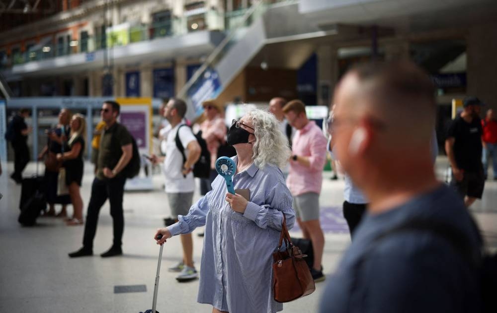 A woman cools herself with a portable fan, during a heatwave, in London, Britain, July 19, 2022. — Reuters pic