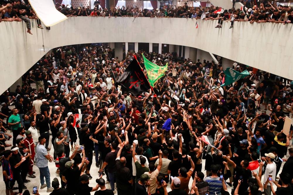 Supporters of cleric Moqtada Sadr wave flags inside Iraq’s parliament in the capital Baghdad’s high-security Green Zone, as they protest against a rival bloc's nomination for prime minister, on July 30, 2022. — AFP pic