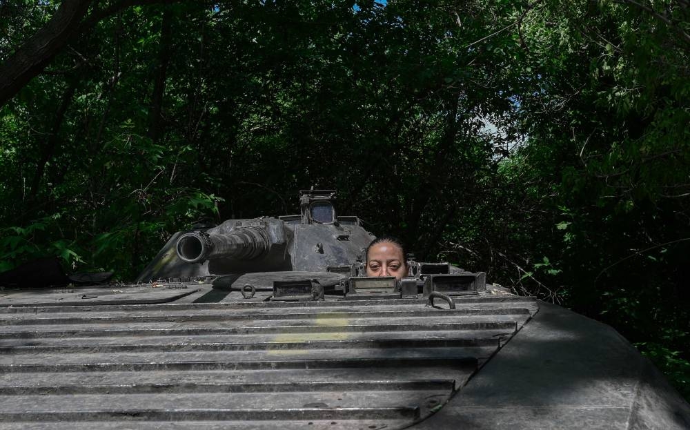 Karina, a former textile worker of Tajik origin, stands next to a military vehicle during an interview with AFP in Donbas region, eastern Ukraine, on July 26, 2022. — AFP pic