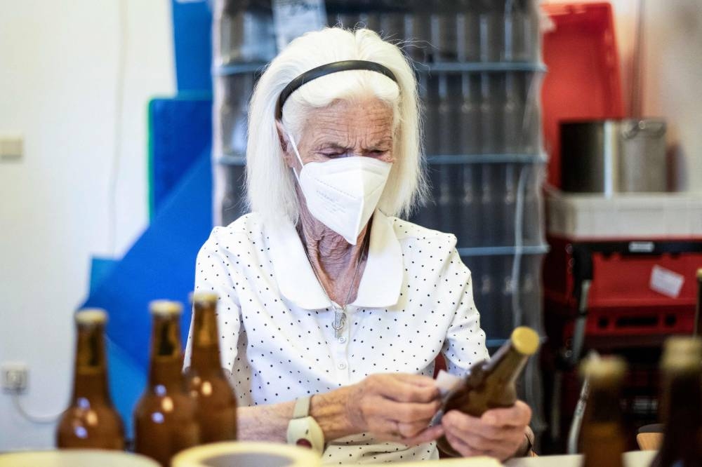 Ingeborg Zeller, resident of the retirement home in Atzgersdorf labels bottles during the weekly beer brewing in Vienna on July 21, 2022. — AFP pic