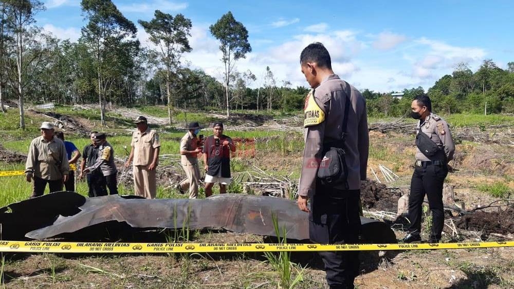 Indonesian police and villagers taking a closer look at the object discovered at Pengadang, a village in Sekayam District of the Sanggau Regency in West Kalimantan. A police line can be seen on the photo, indicating that the police have cordoned off the area. — Suara Kalbar pic via Borneo Post