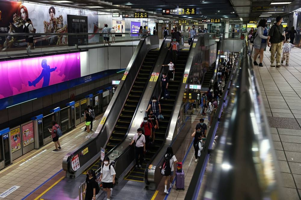 Commuters ride an escalator in an underground metro station, which will be used as an air-raid shelter in the event of an attack, in Taipei July 20, 2022. — Reuters pic