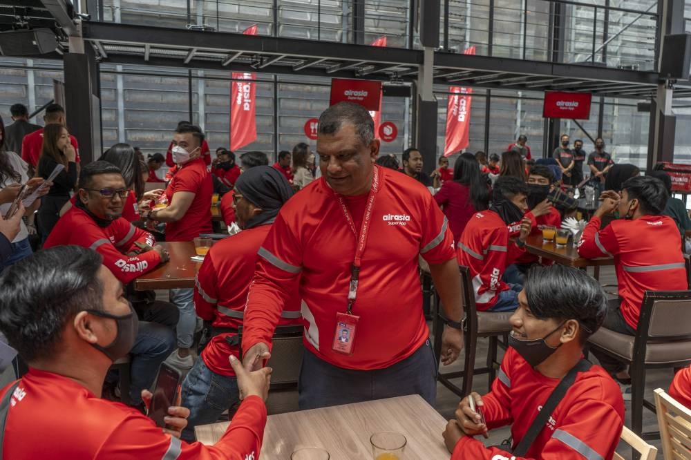 AirAsia chief executive officer Tan Sri Tony Fernandes shares a light moment with riders at Sky Lounge, NU Sentral in Kuala Lumpur, August 4, 2022. — Picture by Shafwan Zaidon